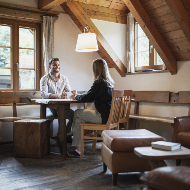 Urige Art zu wohnen im Schwarzwald. Esstisch mit zwei jungen Leuten, die Kaffee trinken.