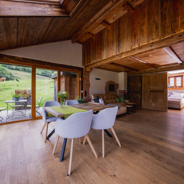 Blick in die Ferienwohnung Alte Backstube mit Esszimmertisch, Couch und Wintergarten. Rechts hinten sieht man hinter der Schiebetür das Boxspringbett.